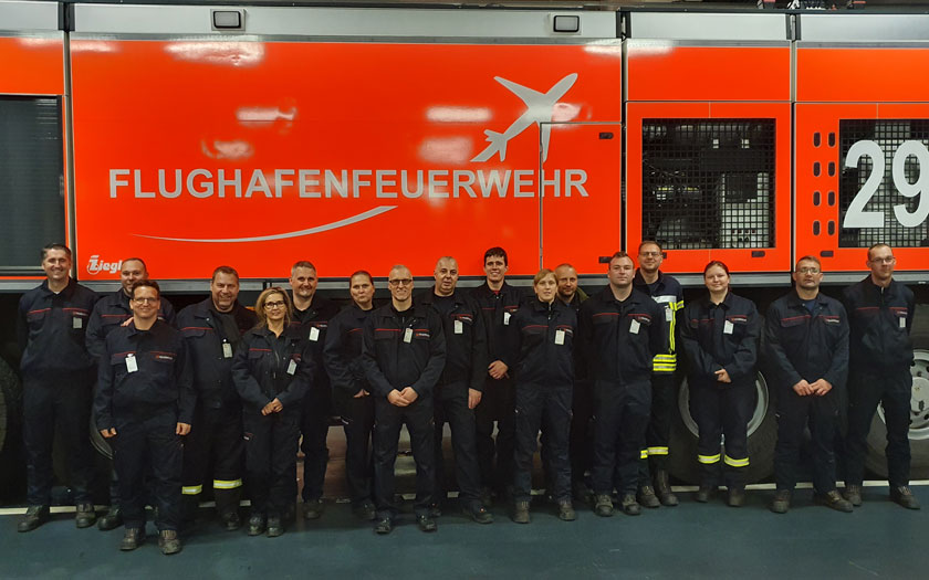 Gruppenfoto vor einem Flugfeldlöschfahrzeug (FLF) der Flughafenfeuerwehr des BER